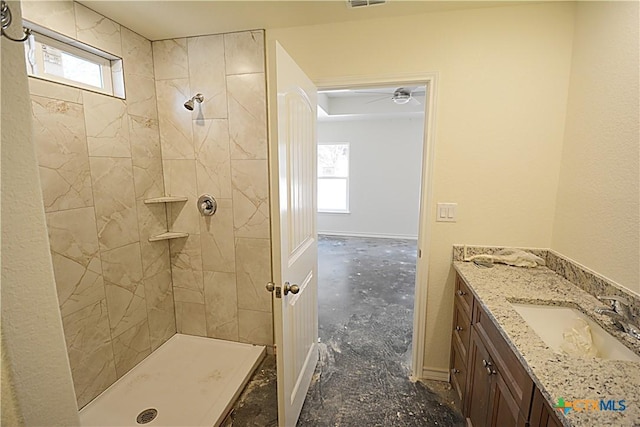 bathroom with vanity, a wealth of natural light, and a tile shower