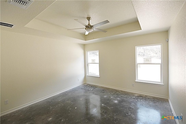 spare room featuring ceiling fan, a tray ceiling, a wealth of natural light, and a textured ceiling