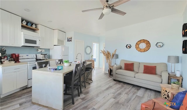 1265 N Ocean Dr Unit 2, Port Lavaca, TX 77979 - kitchen featuring a ceiling fan, white appliances, a breakfast bar area, light wood-style flooring, and white cabinets