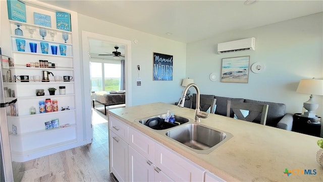 1265 N Ocean Dr Unit 2, Port Lavaca, TX 77979 - kitchen with light wood finished floors, light countertops, a sink, a wall mounted AC, and white cabinetry