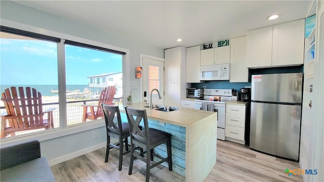 1265 N Ocean Dr Unit 2, Port Lavaca, TX 77979 - kitchen featuring white cabinets, a sink, a kitchen bar, white appliances, and light countertops