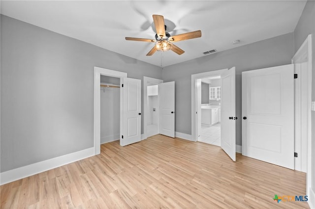 unfurnished bedroom featuring ceiling fan, light hardwood / wood-style flooring, a closet, and connected bathroom