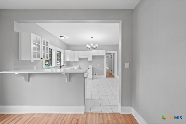 kitchen with kitchen peninsula, white cabinets, a breakfast bar, and an inviting chandelier