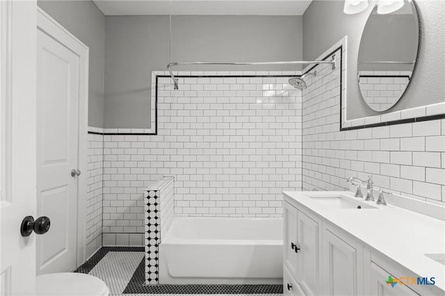 full bathroom featuring vanity, toilet, tiled shower / bath combo, and tile walls