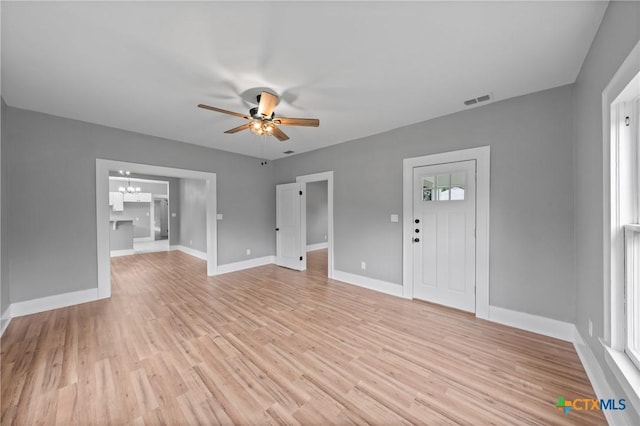 unfurnished living room featuring ceiling fan with notable chandelier and light wood-type flooring