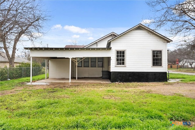 rear view of property with a lawn and a carport