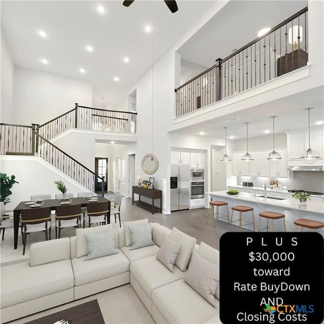 living room featuring a high ceiling, ceiling fan, and sink