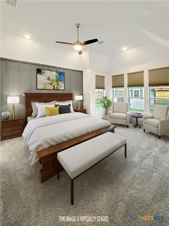 carpeted bedroom featuring multiple windows, visible vents, and a decorative wall