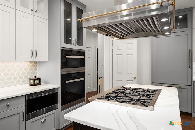 kitchen with dark hardwood / wood-style floors, gray cabinetry, range hood, and light stone counters