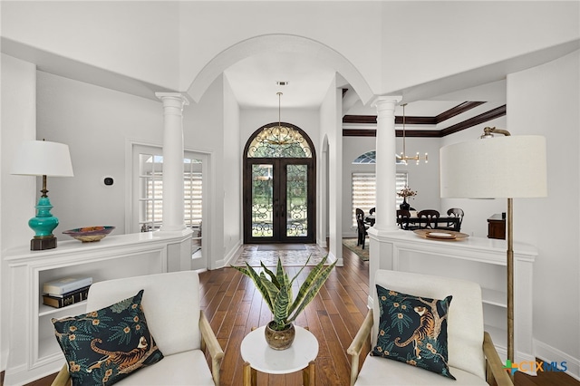 interior space with french doors, dark wood-type flooring, an inviting chandelier, decorative columns, and ornamental molding