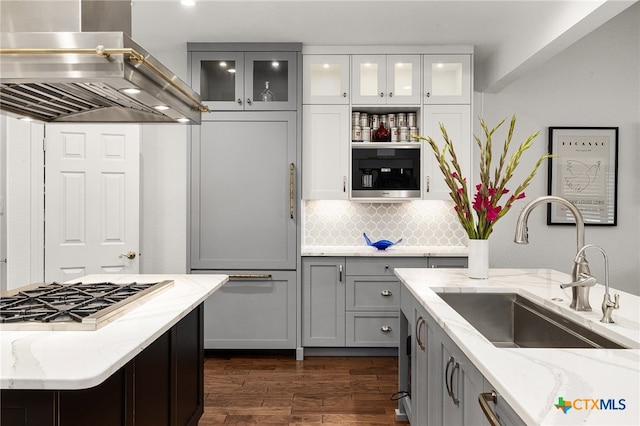 kitchen with stainless steel appliances, wall chimney exhaust hood, sink, dark hardwood / wood-style floors, and light stone countertops