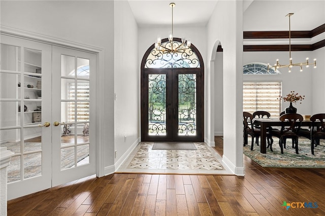 foyer entrance with french doors, dark wood-type flooring, and a chandelier