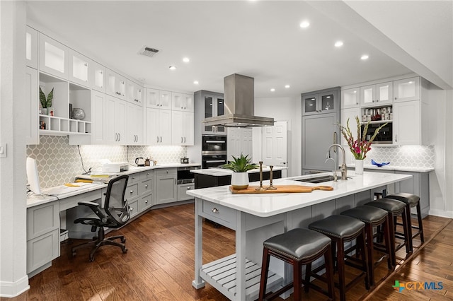 kitchen featuring sink, ventilation hood, a spacious island, gray cabinets, and dark hardwood / wood-style flooring