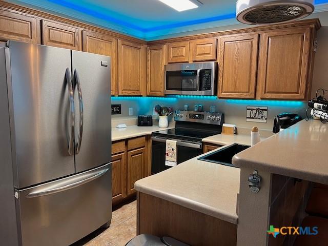 730 E Mather St Unit K203, New Braunfels, TX 78130 - kitchen featuring appliances with stainless steel finishes, brown cabinetry, a peninsula, and light countertops