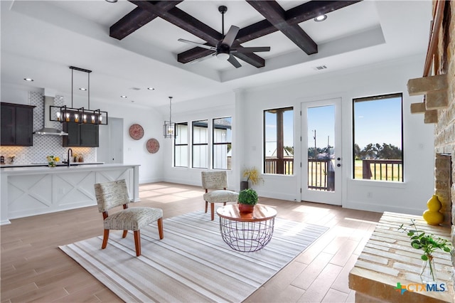 living room with light wood-type flooring, coffered ceiling, ceiling fan, sink, and beam ceiling