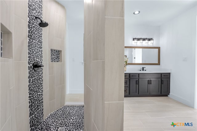 bathroom featuring tile patterned flooring, vanity, and tiled shower