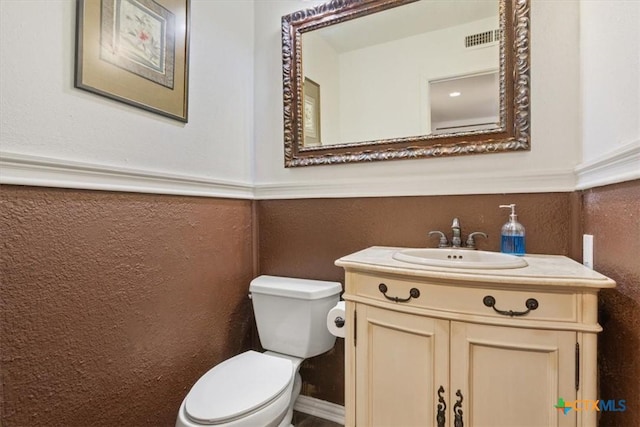 102 Elm Dr, Belton, TX 76513 - half bathroom with visible vents, a wainscoted wall, toilet, and vanity