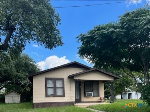 view of front of home with covered porch and a storage shed