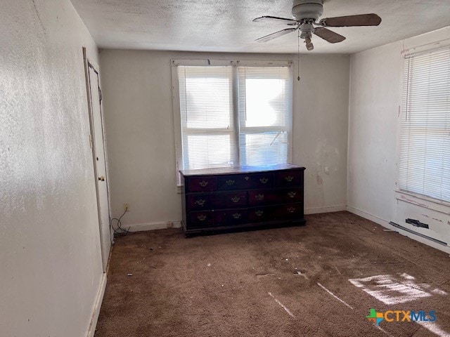 unfurnished bedroom featuring ceiling fan, dark colored carpet, and a textured ceiling