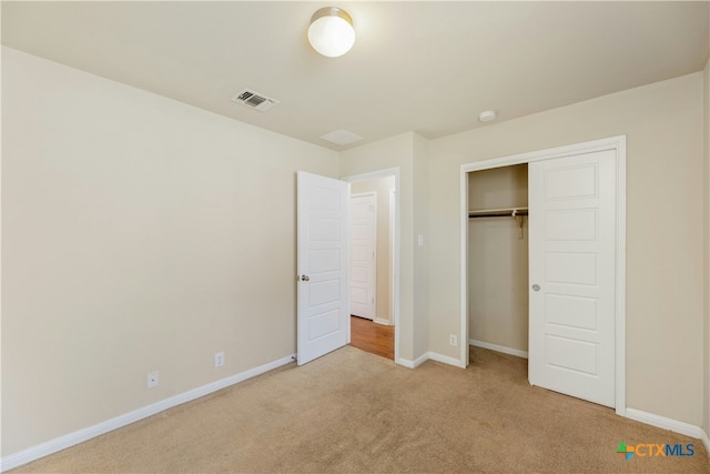 unfurnished bedroom with light colored carpet and a closet