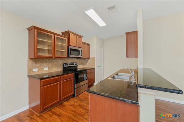 kitchen with kitchen peninsula, sink, light hardwood / wood-style flooring, and appliances with stainless steel finishes