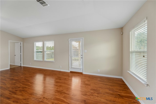 empty room featuring hardwood / wood-style floors, vaulted ceiling, and plenty of natural light