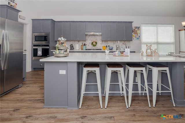 111 Dripping Spg, Victoria, TX 77904 - kitchen with appliances with stainless steel finishes, gray cabinets, a breakfast bar, under cabinet range hood, and light countertops