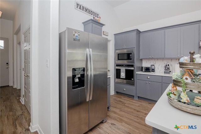 111 Dripping Spg, Victoria, TX 77904 - kitchen featuring appliances with stainless steel finishes, gray cabinets, light countertops, light wood finished floors, and decorative backsplash