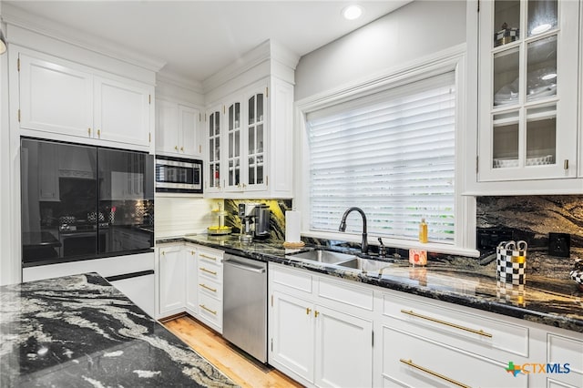 kitchen with white cabinetry, appliances with stainless steel finishes, sink, and dark stone countertops