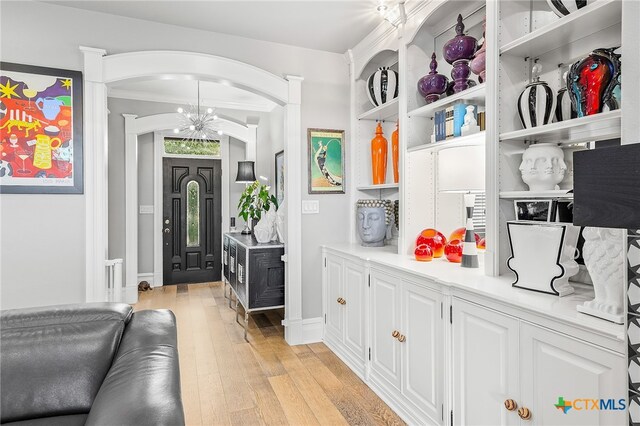 interior space featuring light wood-type flooring, a notable chandelier, and crown molding