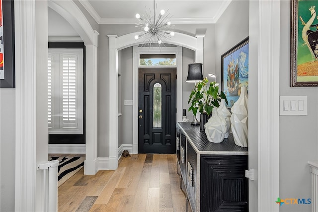 entryway with light hardwood / wood-style flooring, a notable chandelier, and crown molding