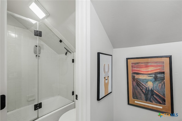 bathroom featuring bath / shower combo with glass door, lofted ceiling, and toilet