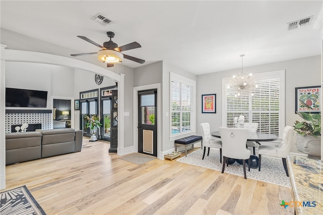 dining space featuring light wood-type flooring and ceiling fan with notable chandelier