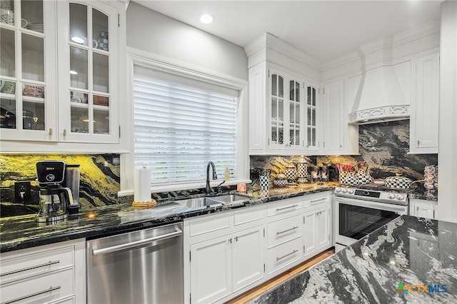 kitchen with stainless steel appliances, dark stone counters, tasteful backsplash, custom range hood, and white cabinetry