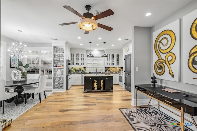 kitchen with a kitchen island, white cabinetry, pendant lighting, and light hardwood / wood-style flooring