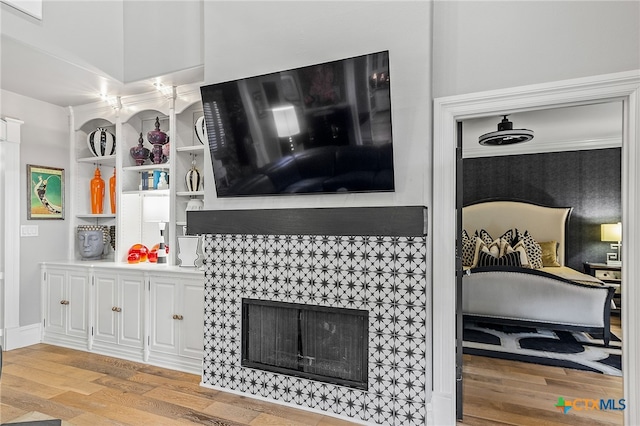 living room with a fireplace, light hardwood / wood-style floors, and crown molding