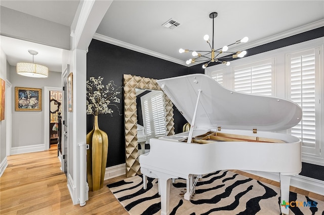 miscellaneous room with a chandelier, a wealth of natural light, light hardwood / wood-style floors, and crown molding