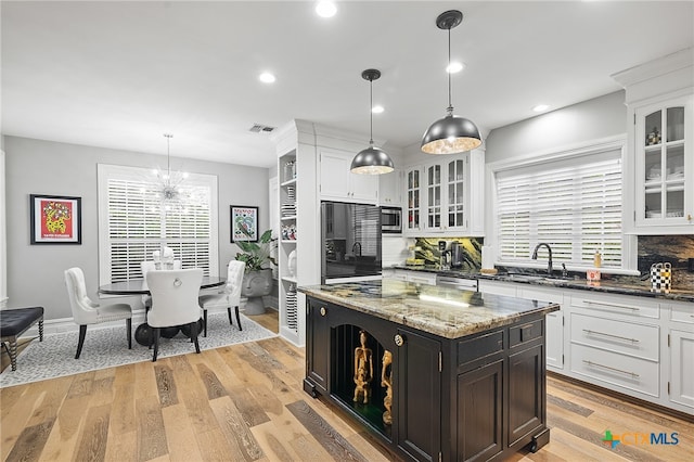 kitchen with black refrigerator, decorative backsplash, decorative light fixtures, and a kitchen island