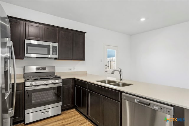 kitchen featuring sink, stainless steel appliances, kitchen peninsula, light hardwood / wood-style floors, and dark brown cabinets