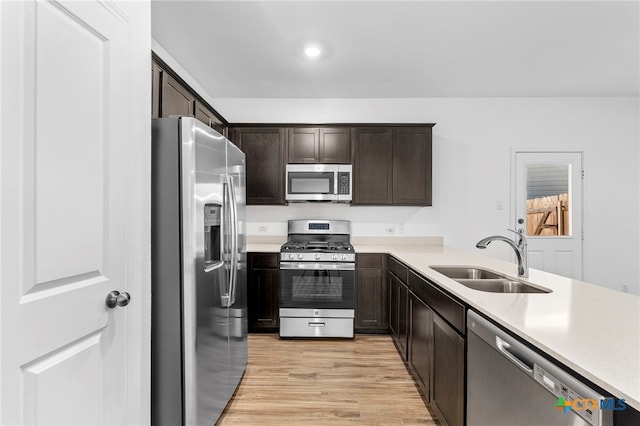 kitchen featuring sink, light wood-type flooring, dark brown cabinets, and appliances with stainless steel finishes