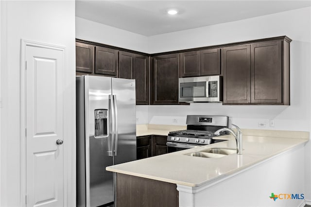 kitchen featuring kitchen peninsula, dark brown cabinets, stainless steel appliances, and sink