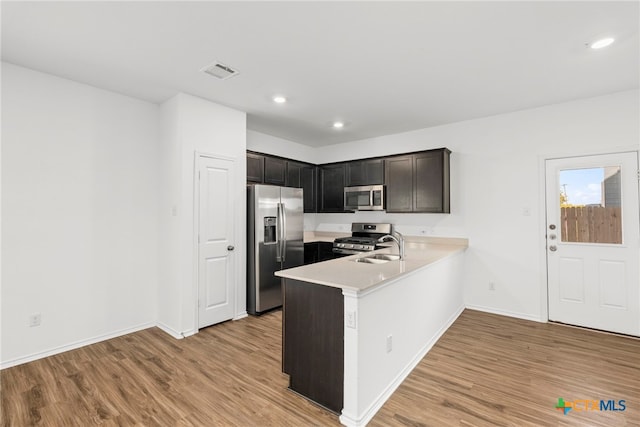 kitchen featuring kitchen peninsula, sink, light wood-type flooring, and appliances with stainless steel finishes