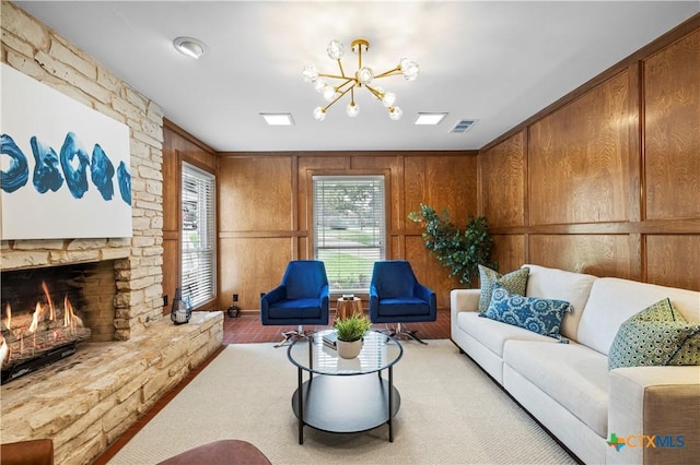 living room featuring a chandelier, wood walls, and a stone fireplace