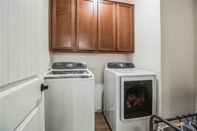 washroom featuring cabinets, dark hardwood / wood-style floors, and washing machine and clothes dryer