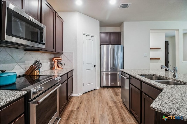 kitchen featuring sink, light hardwood / wood-style flooring, appliances with stainless steel finishes, dark brown cabinets, and light stone counters