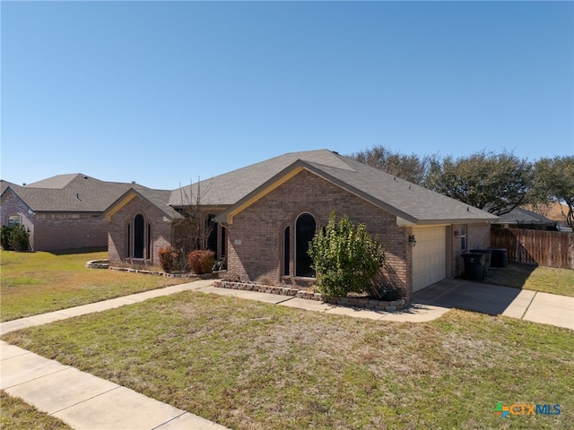 ranch-style house featuring driveway, brick siding, an attached garage, fence, and a front yard