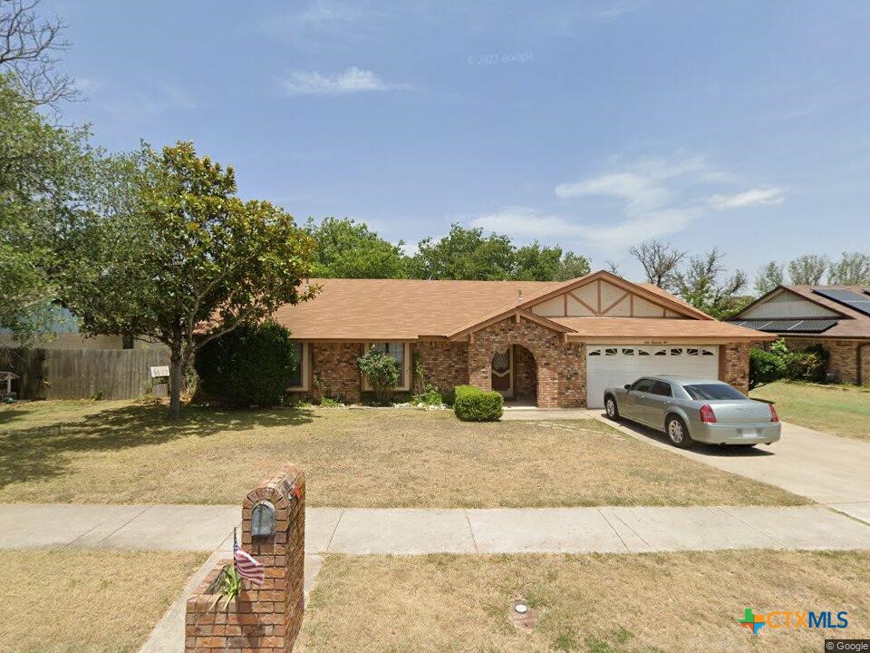single story home featuring a garage, fence, concrete driveway, a front yard, and brick siding