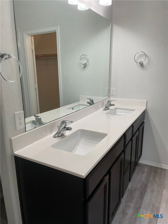 2411 Pintail Loop, Copperas Cove, TX 76522 - bathroom featuring double vanity, wood finished floors, a spacious closet, and baseboards