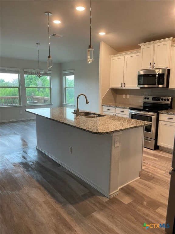 2411 Pintail Loop, Copperas Cove, TX 76522 - kitchen featuring appliances with stainless steel finishes, a sink, a kitchen island with sink, stone counters, and white cabinetry