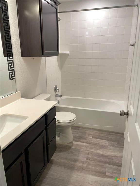 2411 Pintail Loop, Copperas Cove, TX 76522 - bathroom featuring vanity, toilet, wood finished floors, tub / shower combination, and a textured wall